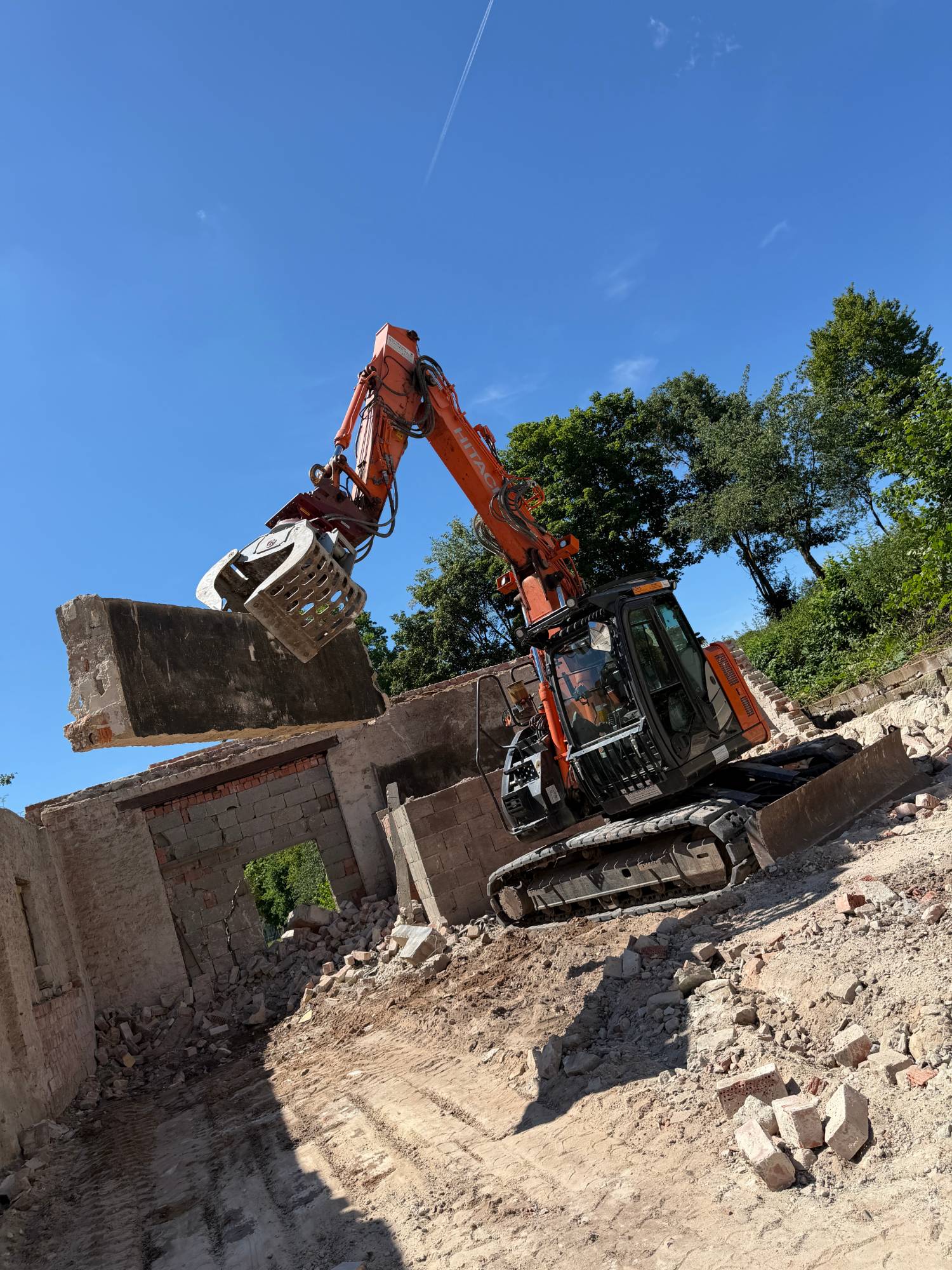 Bagger mit Sortiergreifer hebt beim Abriss eine Betonplatte aus dem Mauerwerk