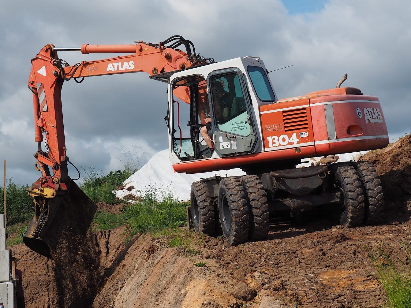 Mobilbagger hebt einen Graben am Rand einer Baustelle aus