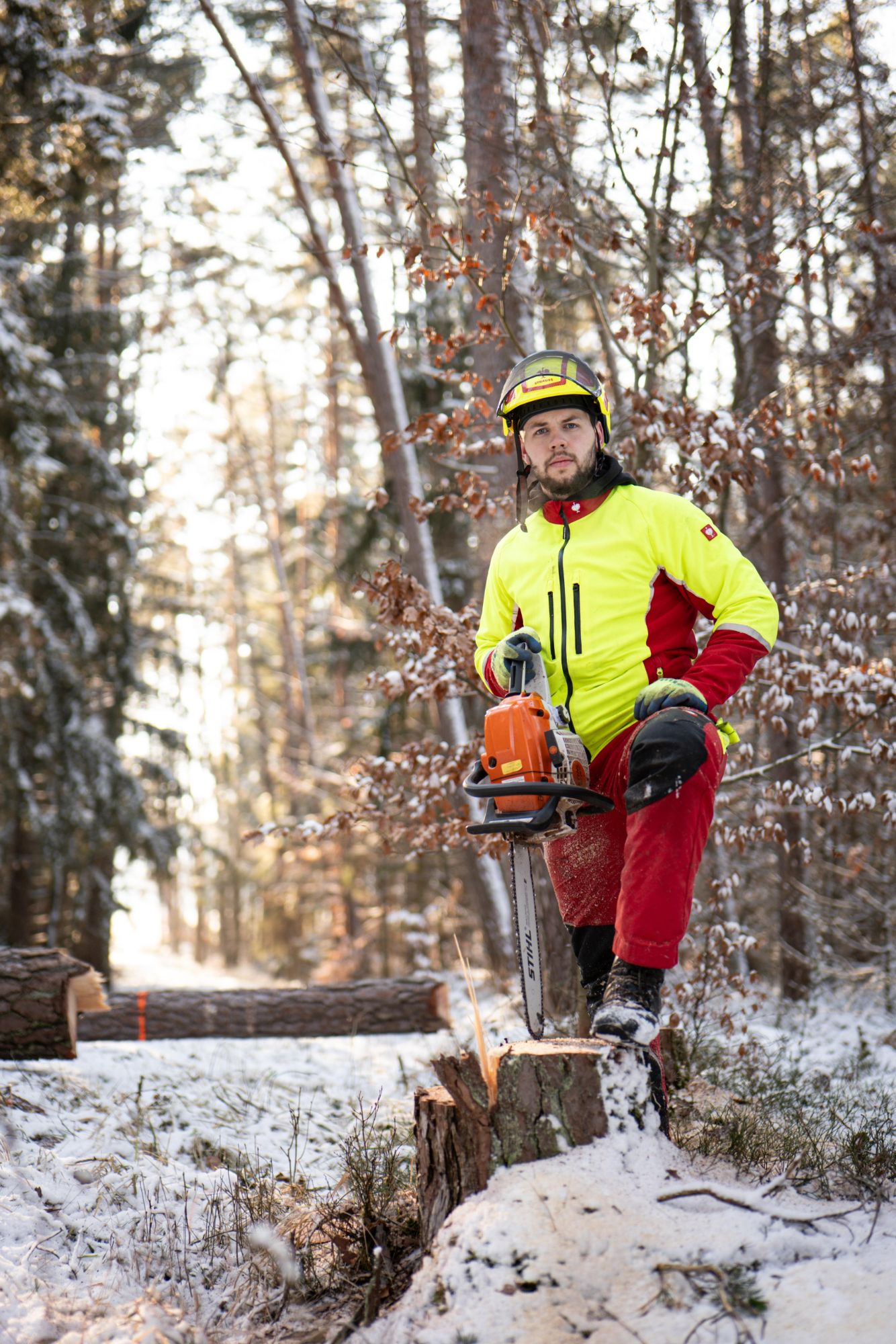 Markus Bauer in Schnittschutzkleidung und Helm mit Kettensäge im verschneiten Wald