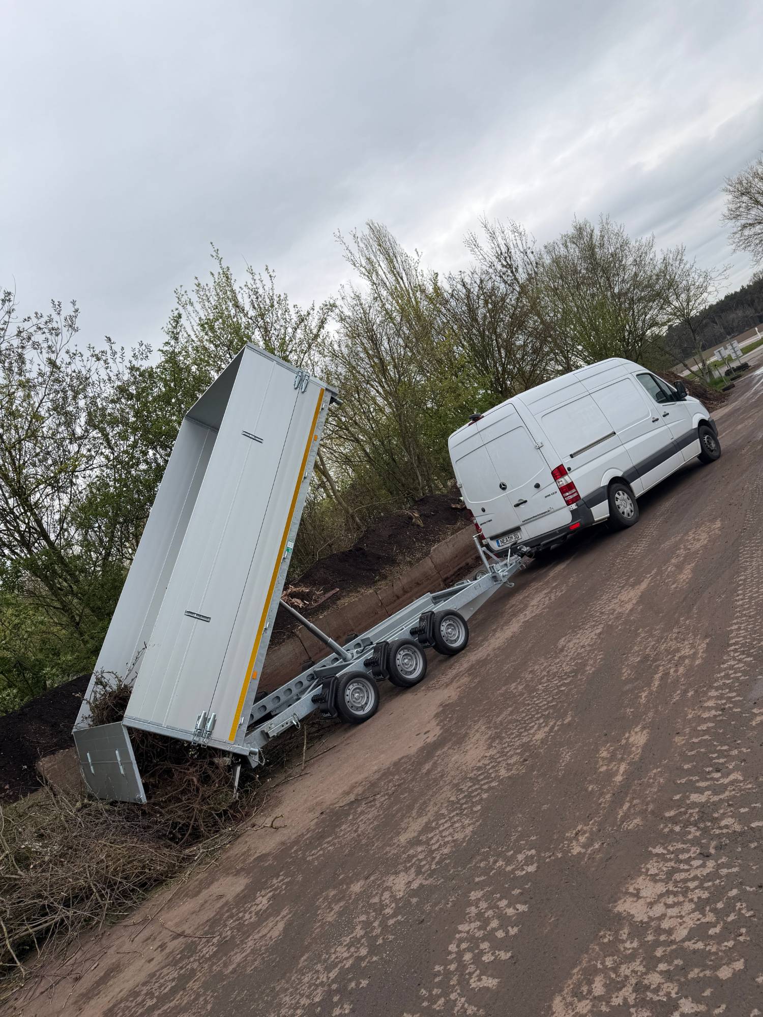 Transporter mit hochgekipptem Dreiseitenkipper lädt Grünschnitt auf einem Kompostplatz ab